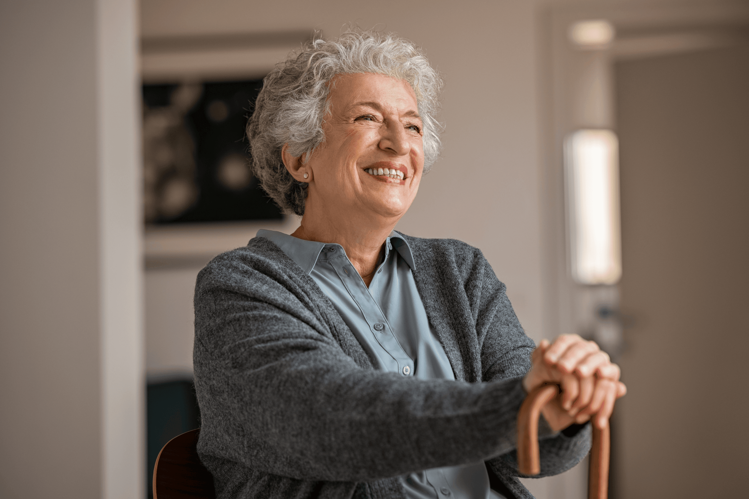 An older woman smiling while resting on her walking cane