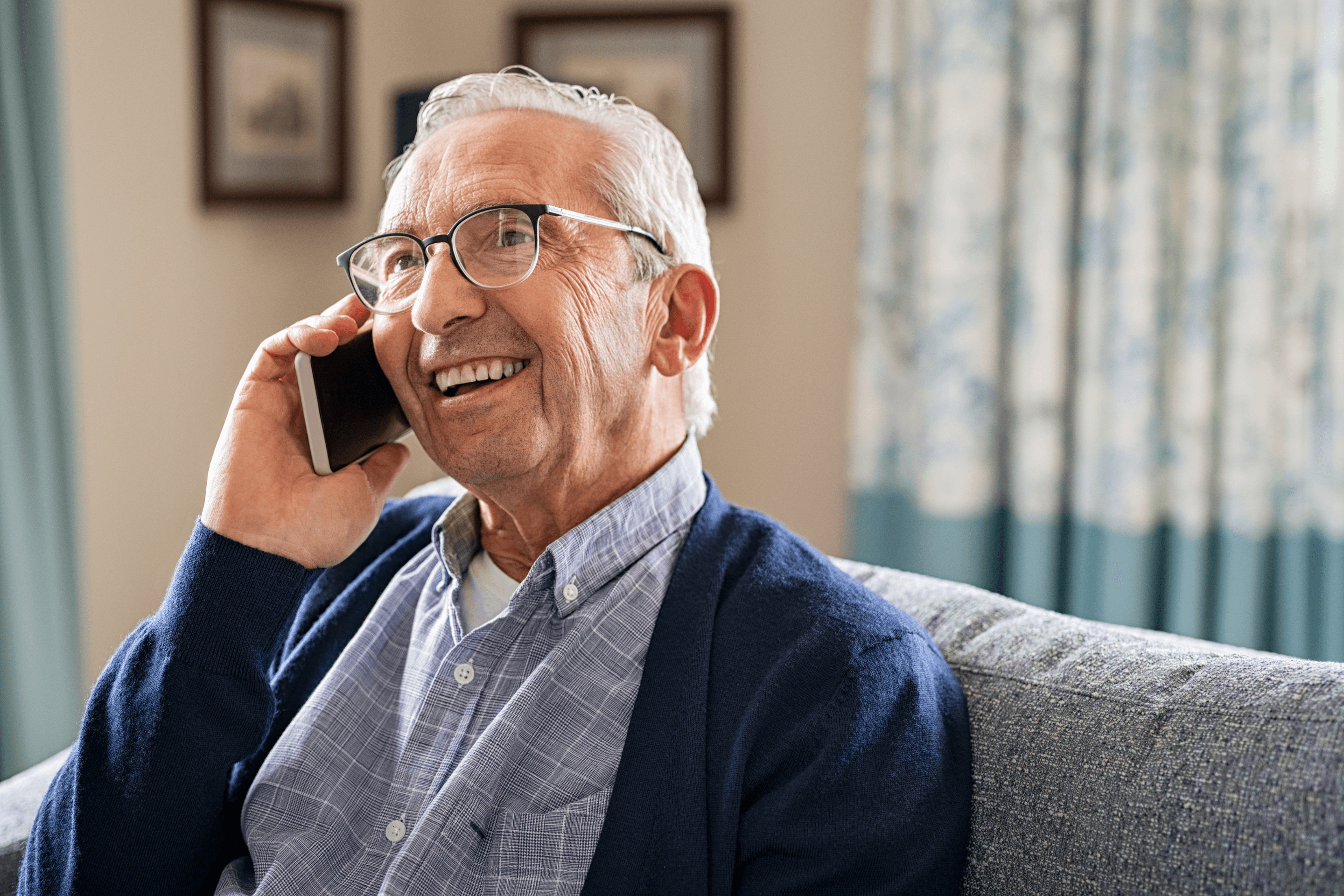 An older man smiling while talking on the phone
