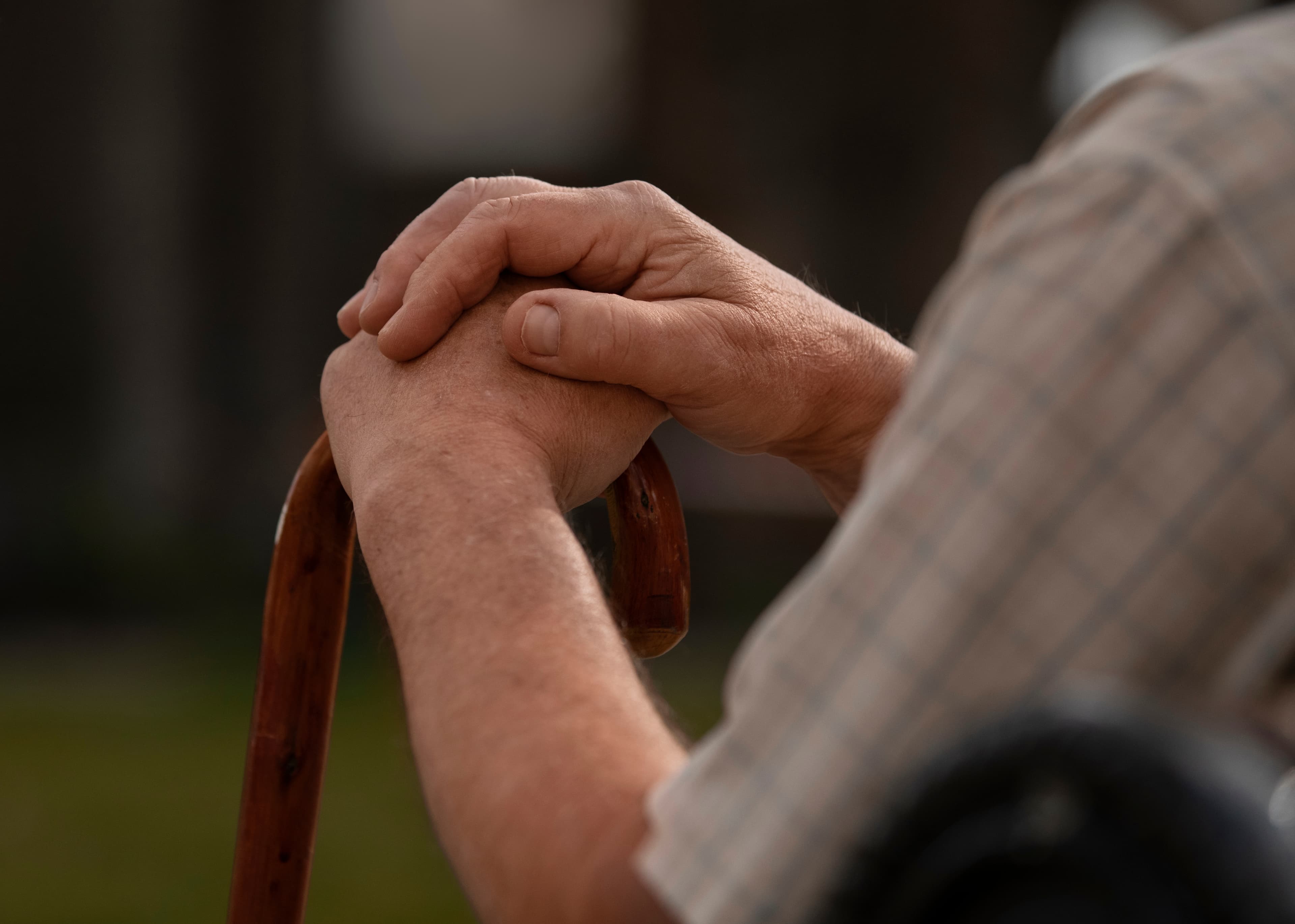 An older person's hands held gently by a caregiver